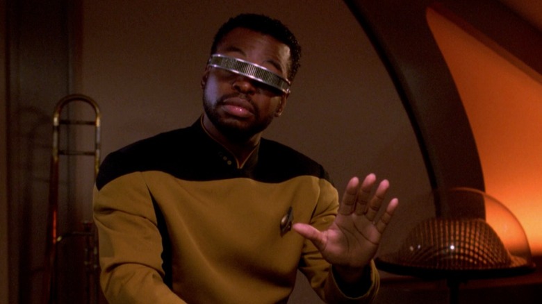 Geordi wearing VISOR, hand up